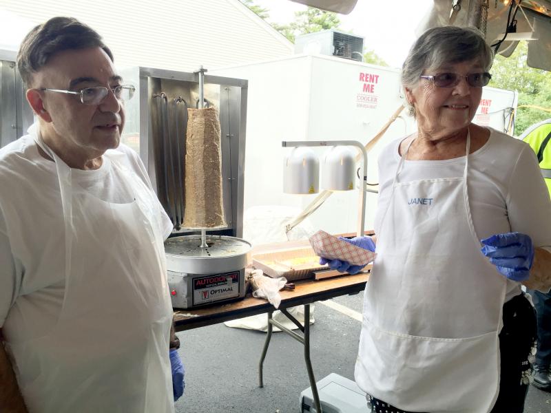 George Kontanis and Janet Peters volunteer at the festival. Behind them, a traditional gyro -- a lamb-beef mix, said Kontanis -- waits to be cut. BY ANGIE HILSMAN